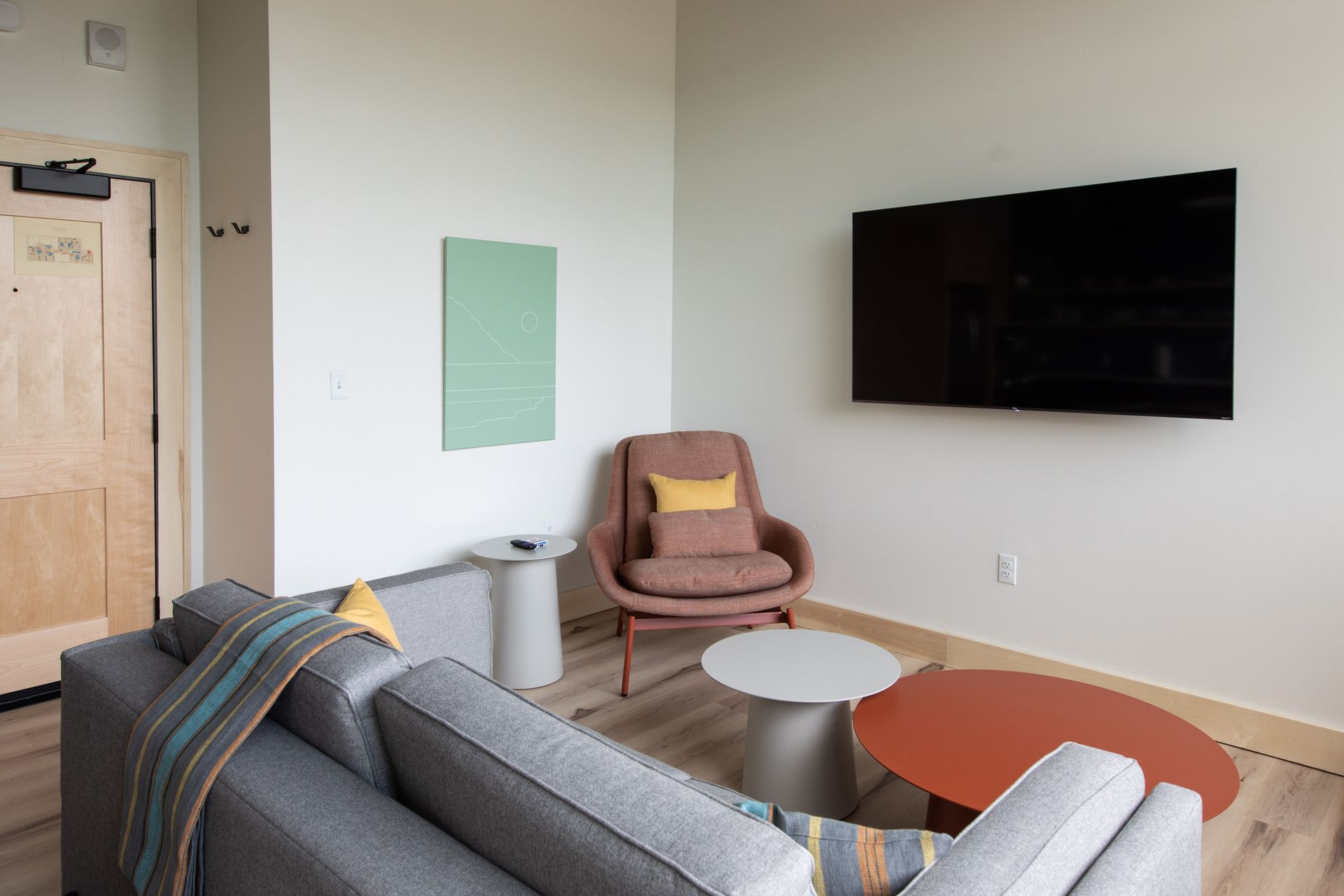 A living room with a couch , chair , tables and a flat screen tv.