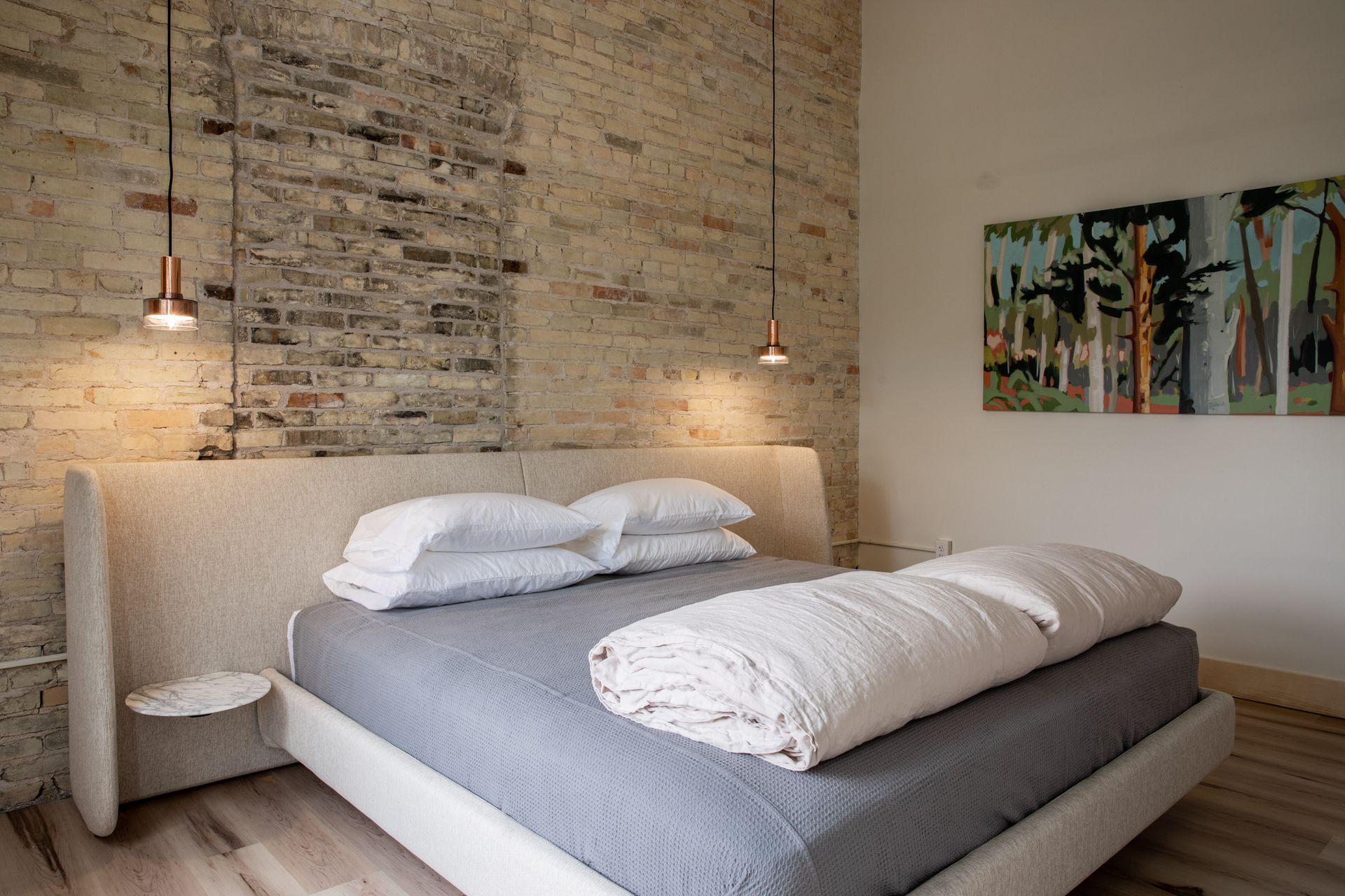 A bedroom with a bed and a painting on the wall.