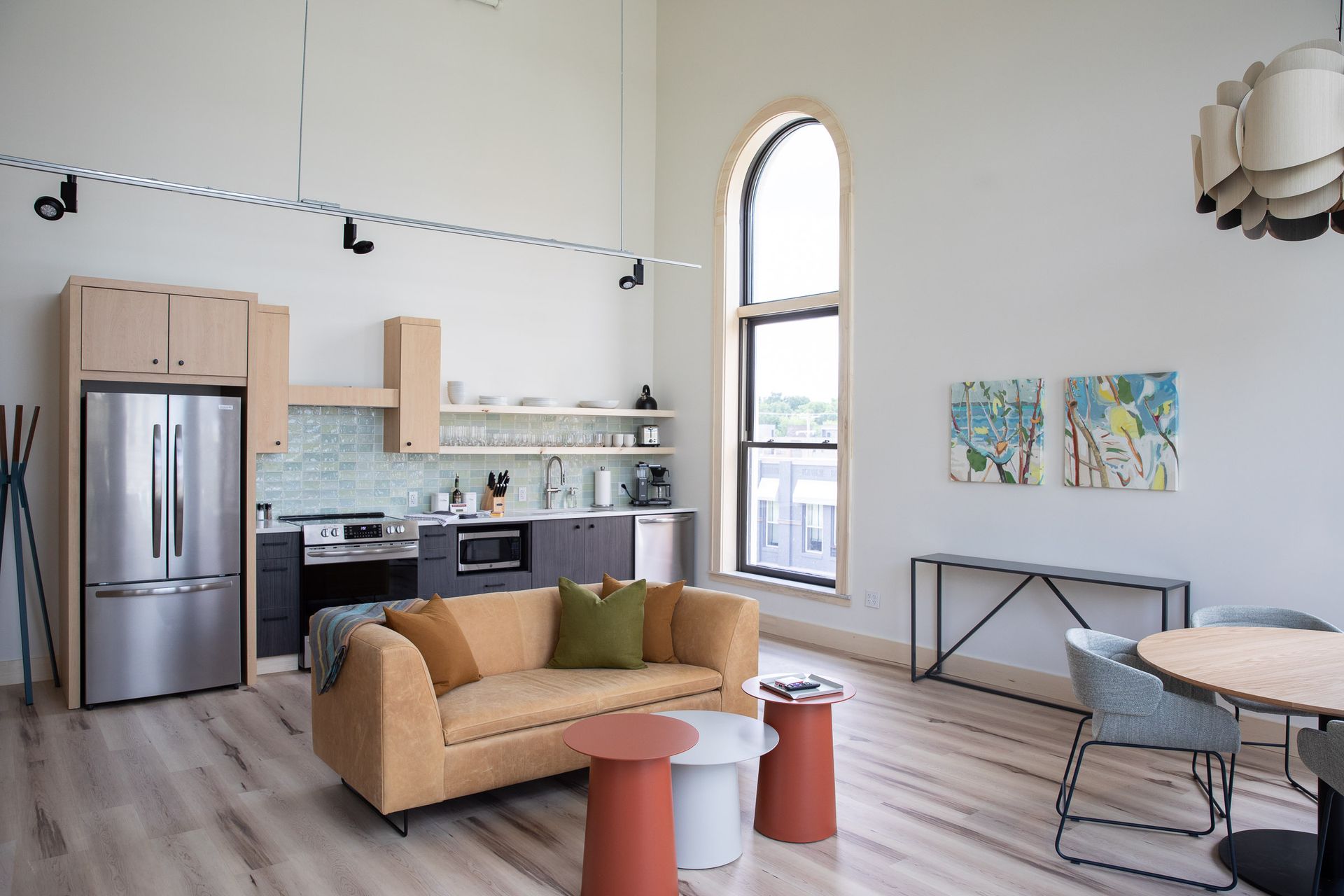 A living room with a couch , table , chairs and a refrigerator.