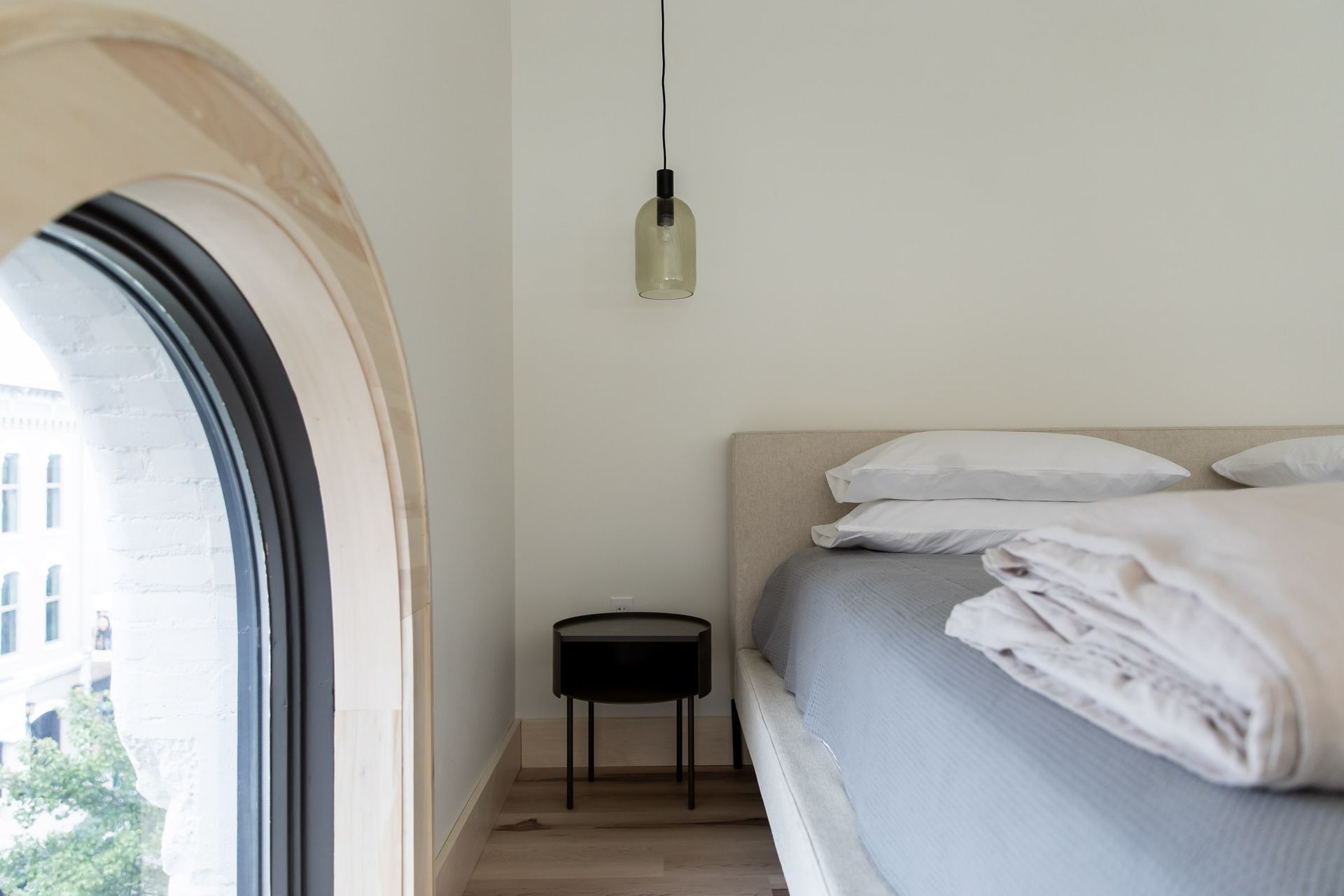 A bedroom with a bed , nightstand , and window.