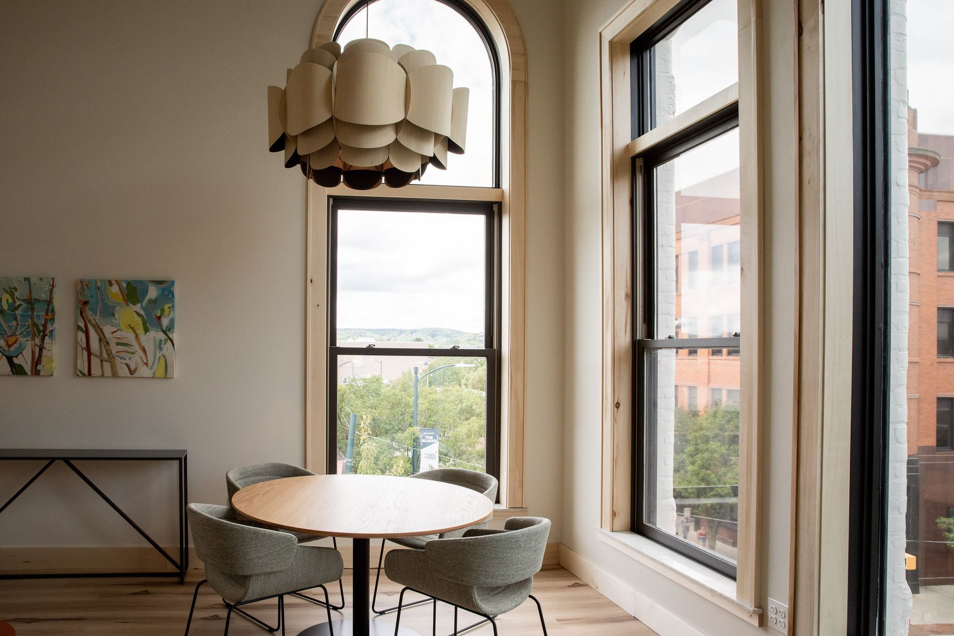 A dining room with a round table and chairs and a large window.