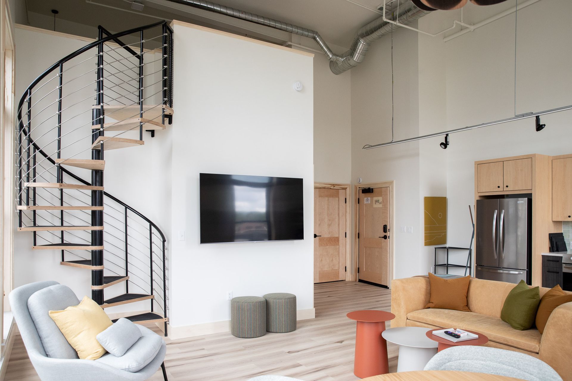 A living room with a spiral staircase and a flat screen tv on the wall.