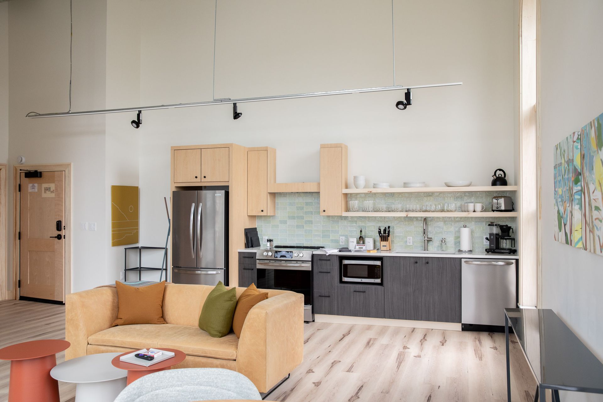 A living room with a couch and a kitchen with stainless steel appliances.