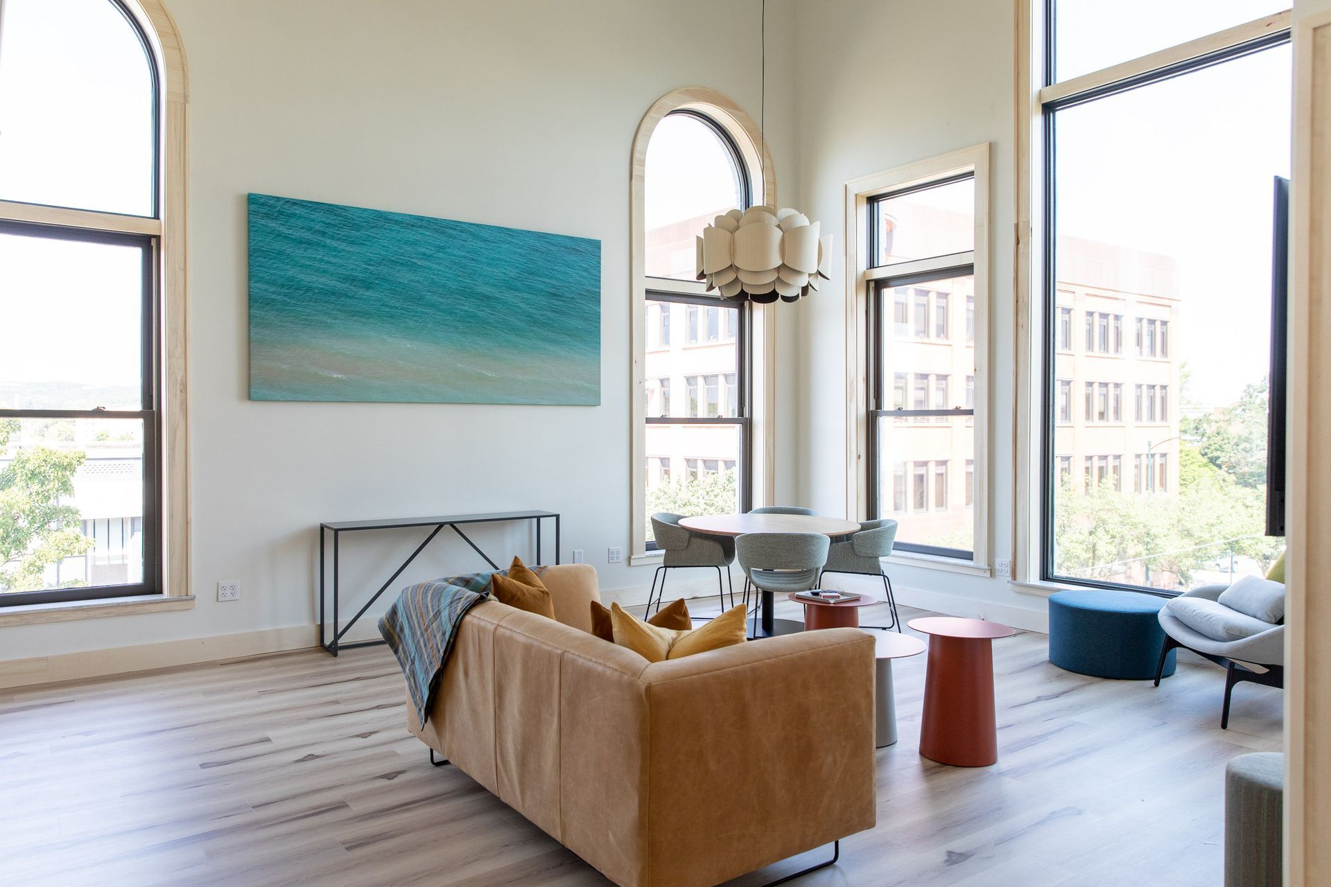 A living room with a couch , table , chairs and a painting on the wall.