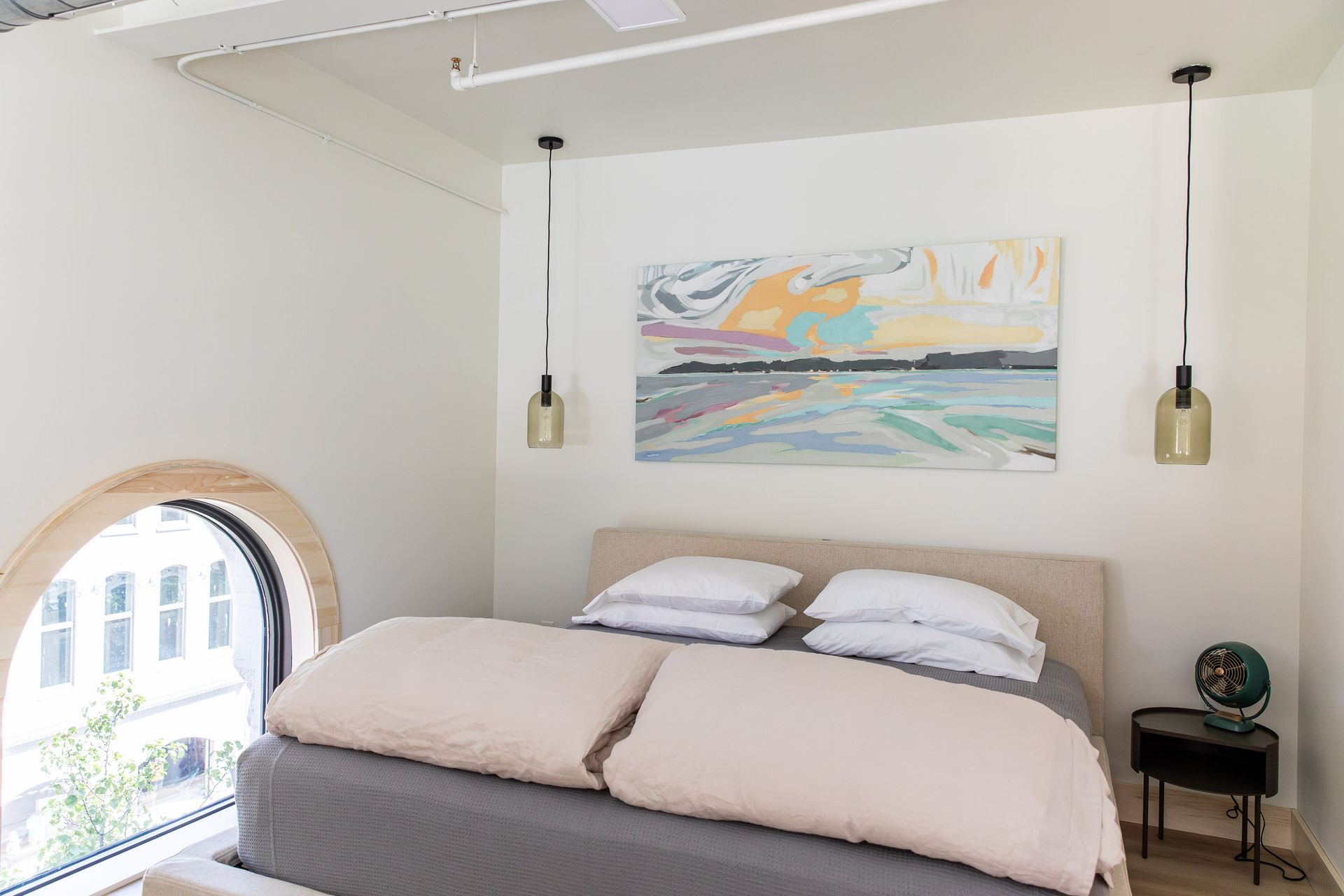 A bedroom with a bed and a painting on the wall above it.