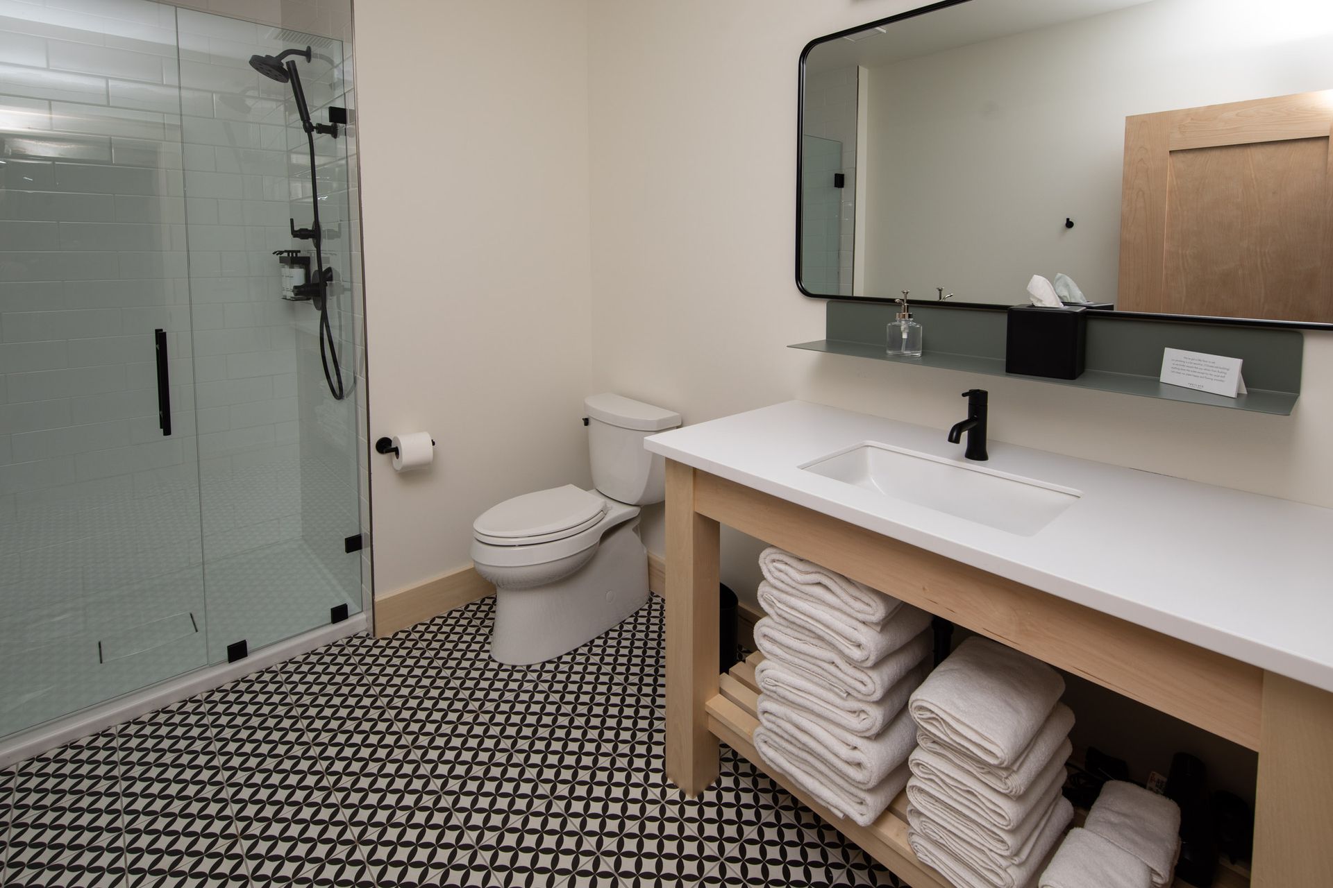 A bathroom with a toilet , sink , mirror and shower.
