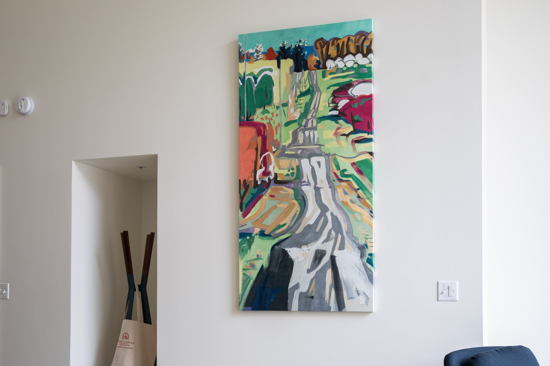A large painting is hanging on a wall in a living room.