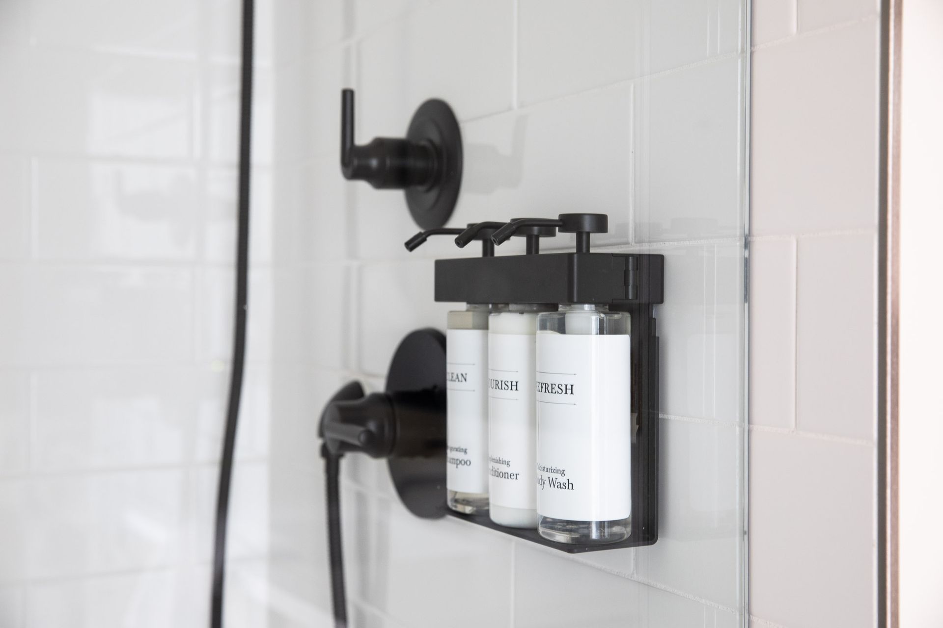 There are three bottles of shampoo and conditioner in the shower.