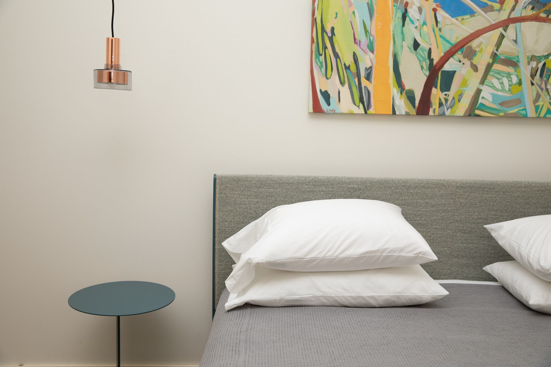 A bedroom with a painting on the wall above the bed