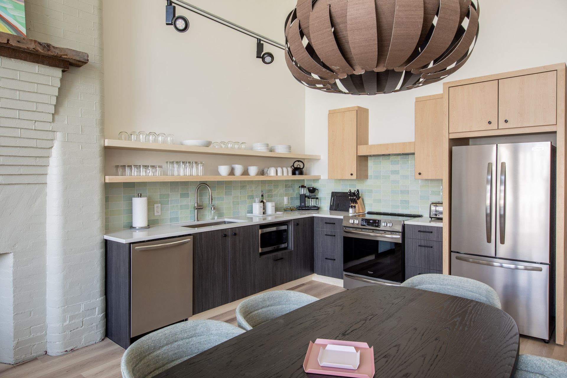 A kitchen with a table and chairs and a stainless steel refrigerator