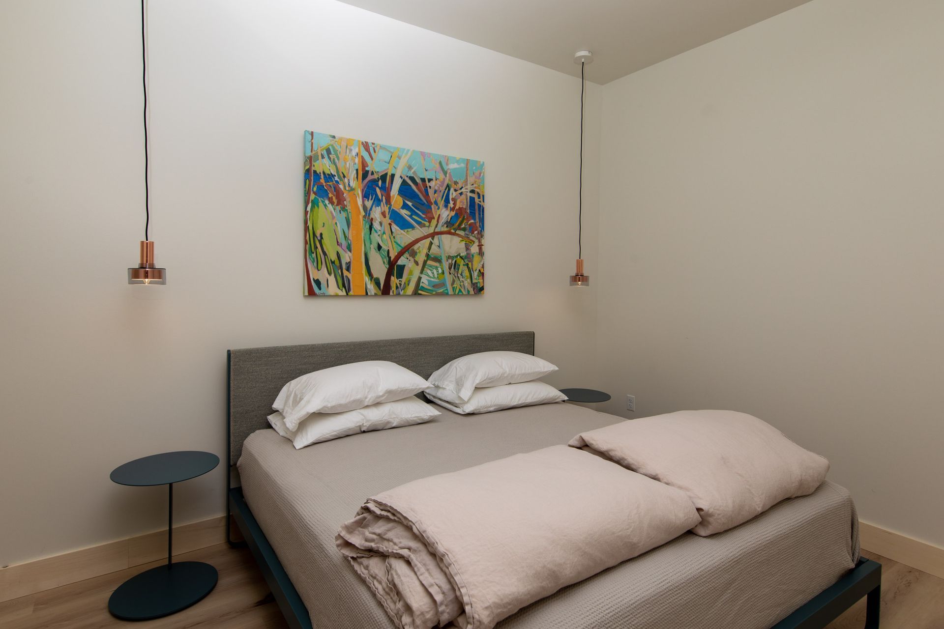 A bedroom with a large bed and a painting on the wall above it.