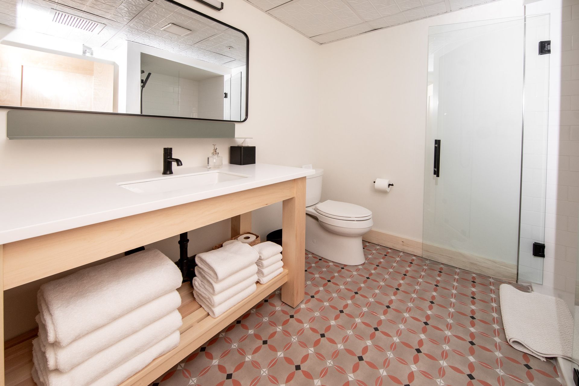 A bathroom with a toilet , sink , mirror and towels.