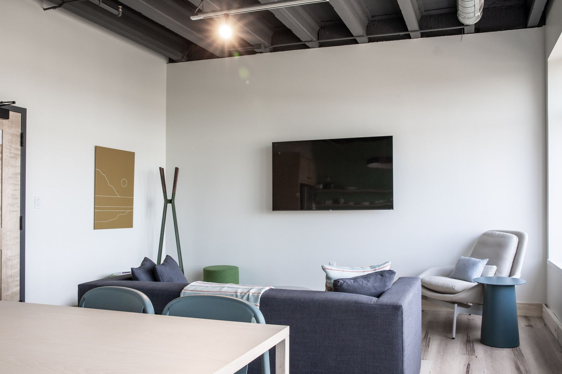 A living room with a couch , chair , table and television on the wall.