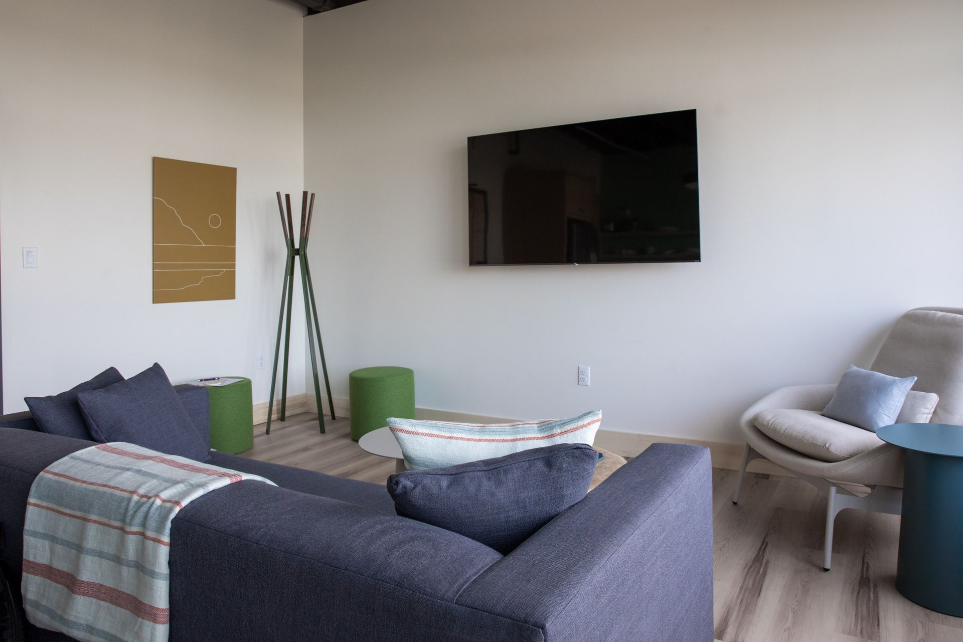 A living room with a couch , chair , table and television on the wall.