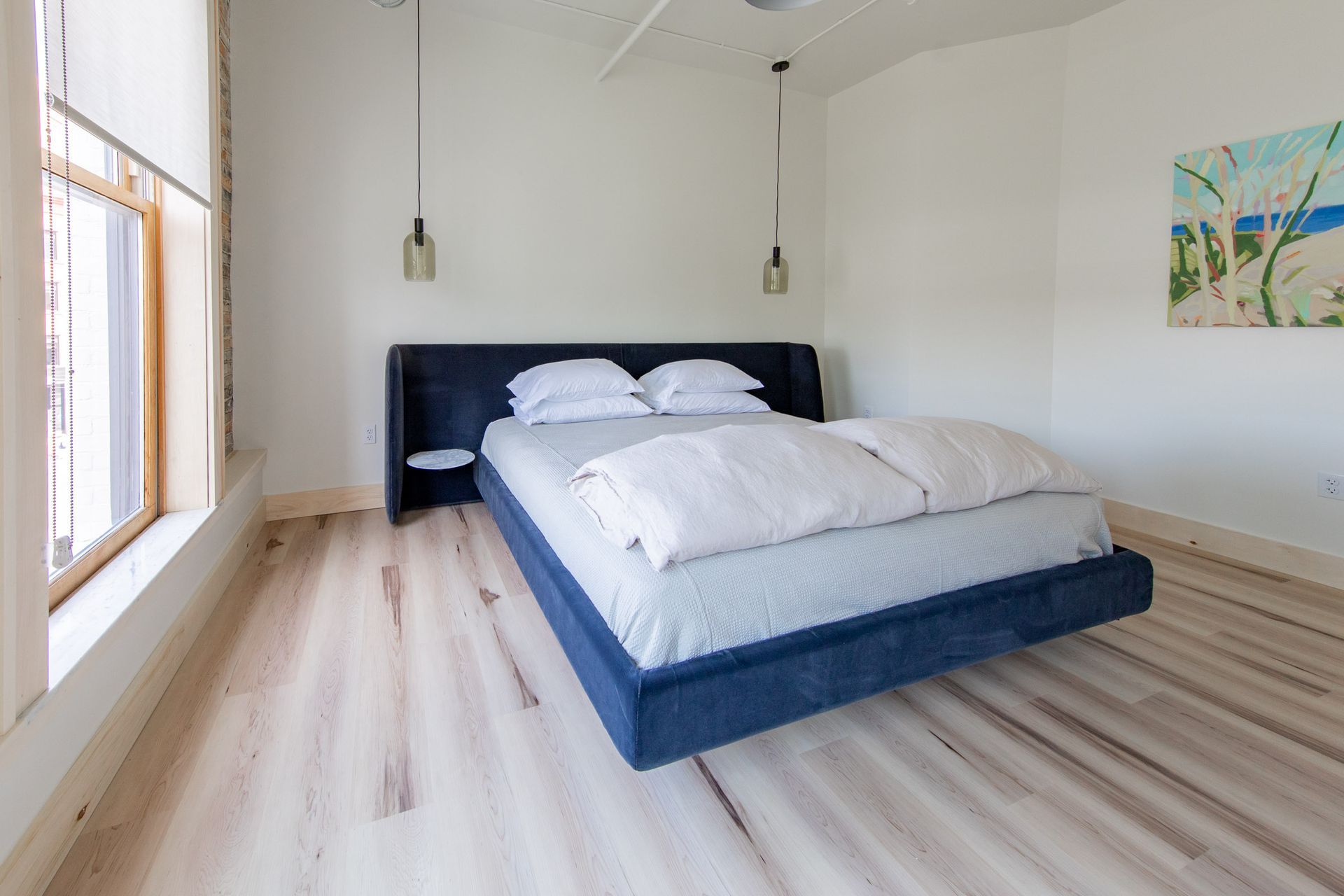 A bedroom with a large bed and a painting on the wall.