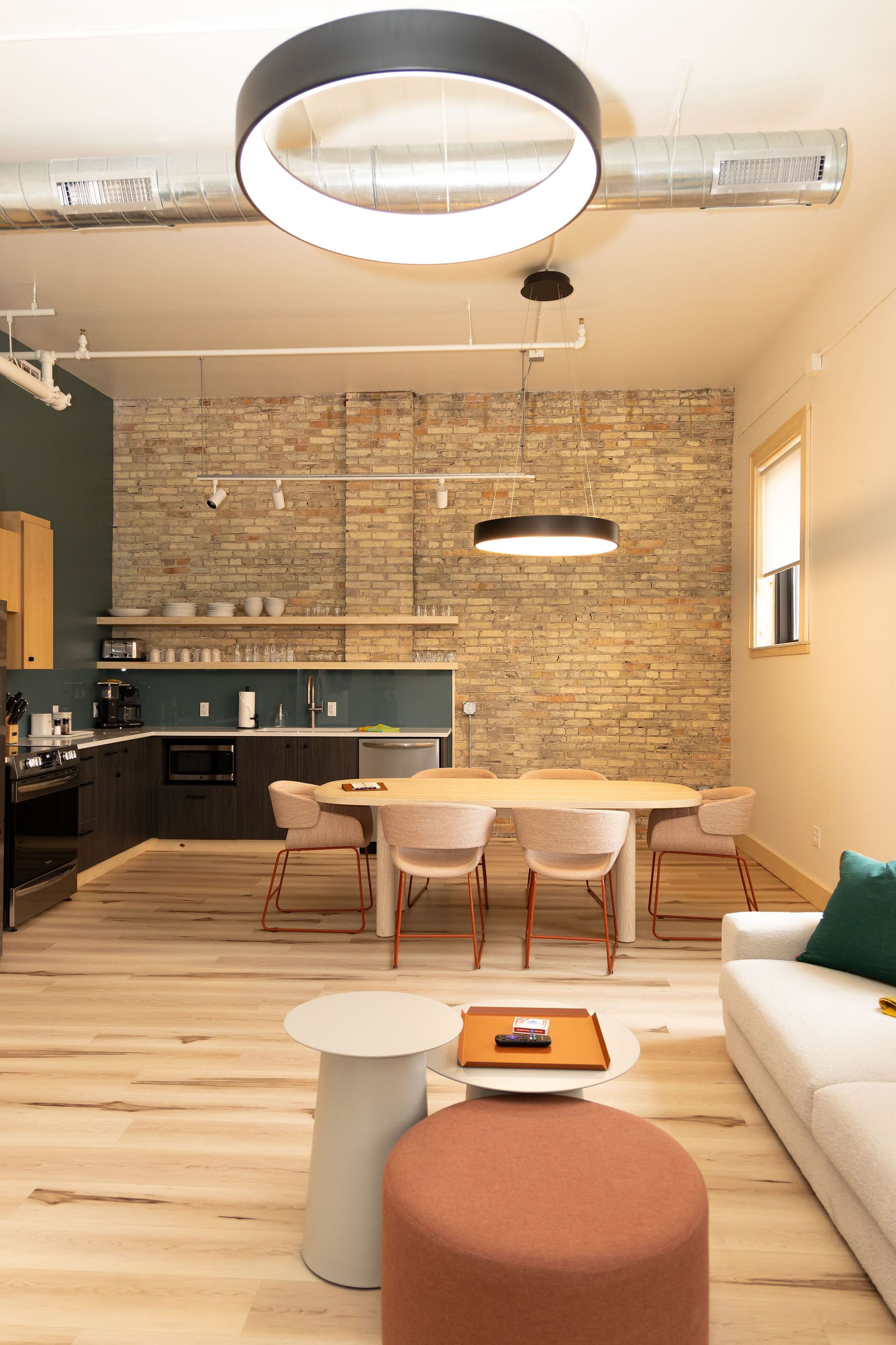 A living room with a couch , table , chairs and ottomans.