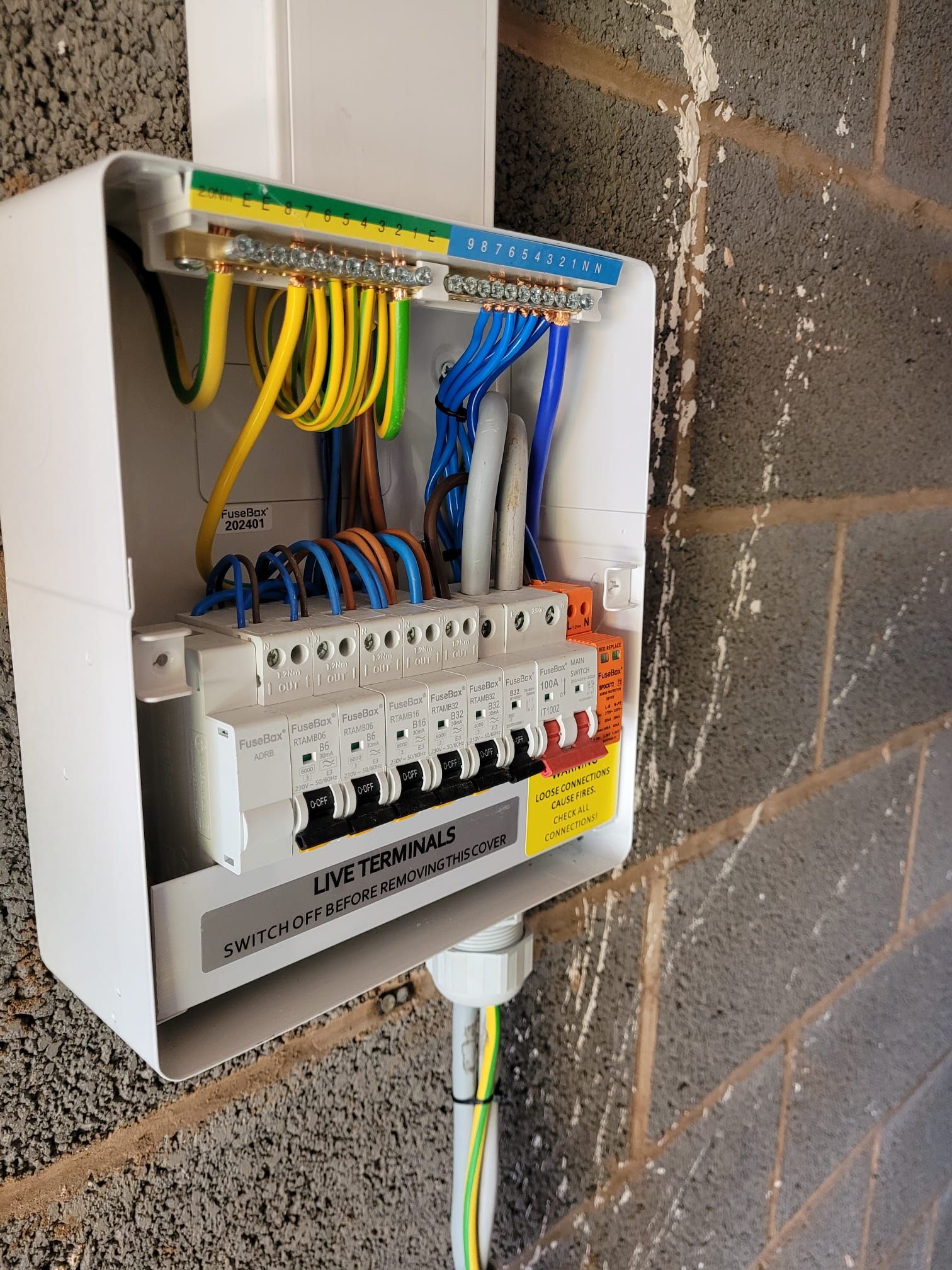 A man is holding a pair of pliers and working on an electrical outlet on a wall.