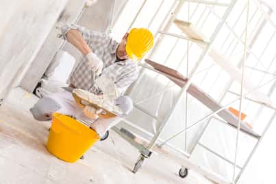 Painter kneeling with a tray of  spackling