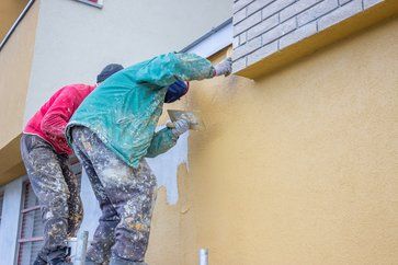 Two painters working on exterior stucco