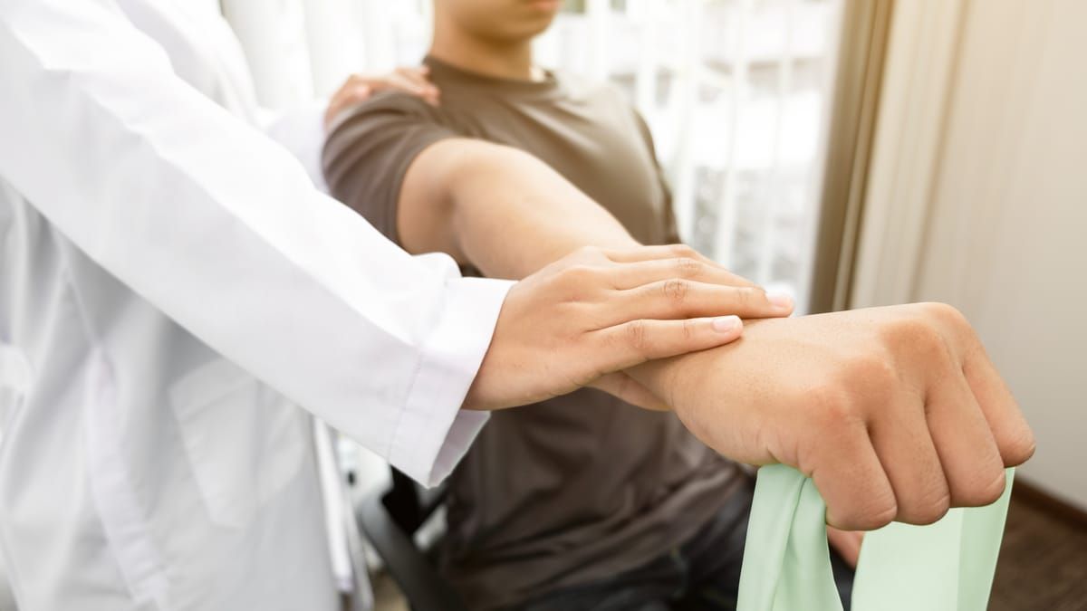 A doctor is examining a patient 's arm with a rubber band.