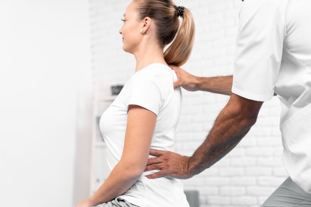 A woman is getting a massage from a man in a white shirt.