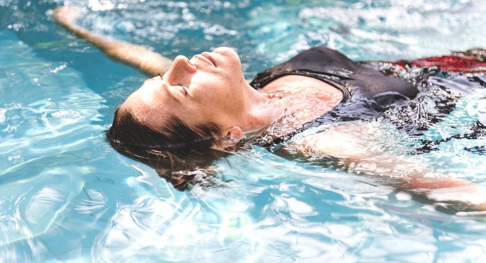 A woman is floating on her back in a swimming pool.