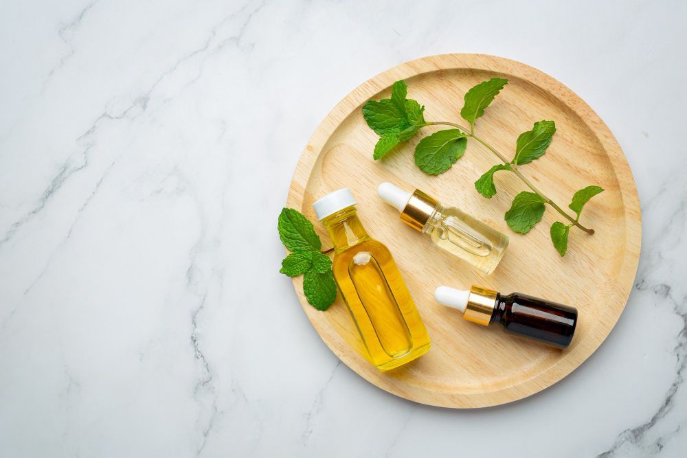 Three bottles of essential oils and mint leaves on a wooden tray.