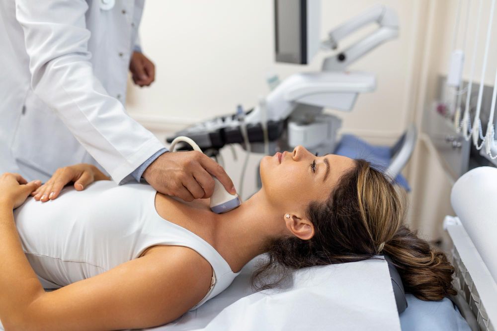 A woman is getting an ultrasound of her neck by a doctor.