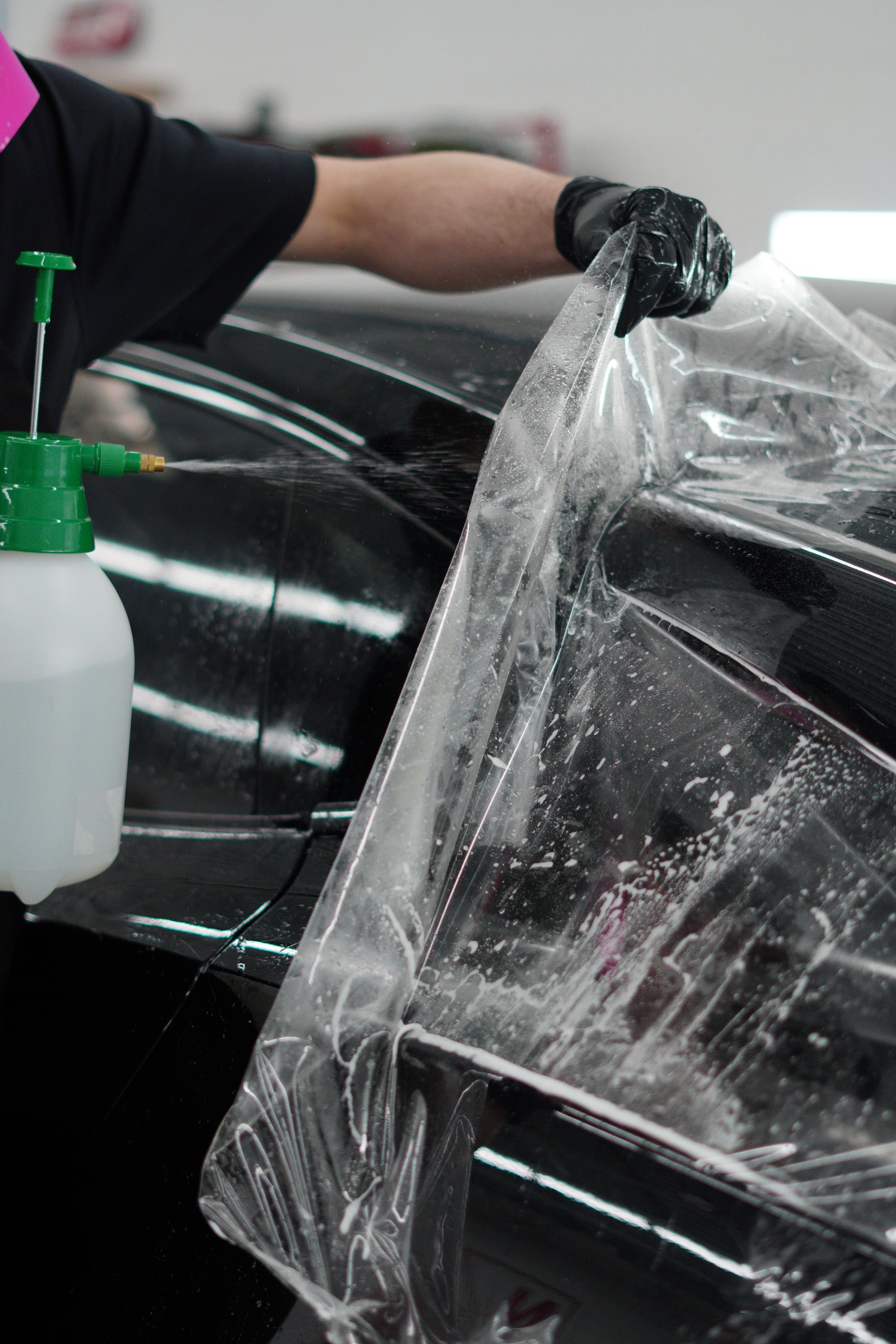 A person is wrapping a car with plastic wrap.