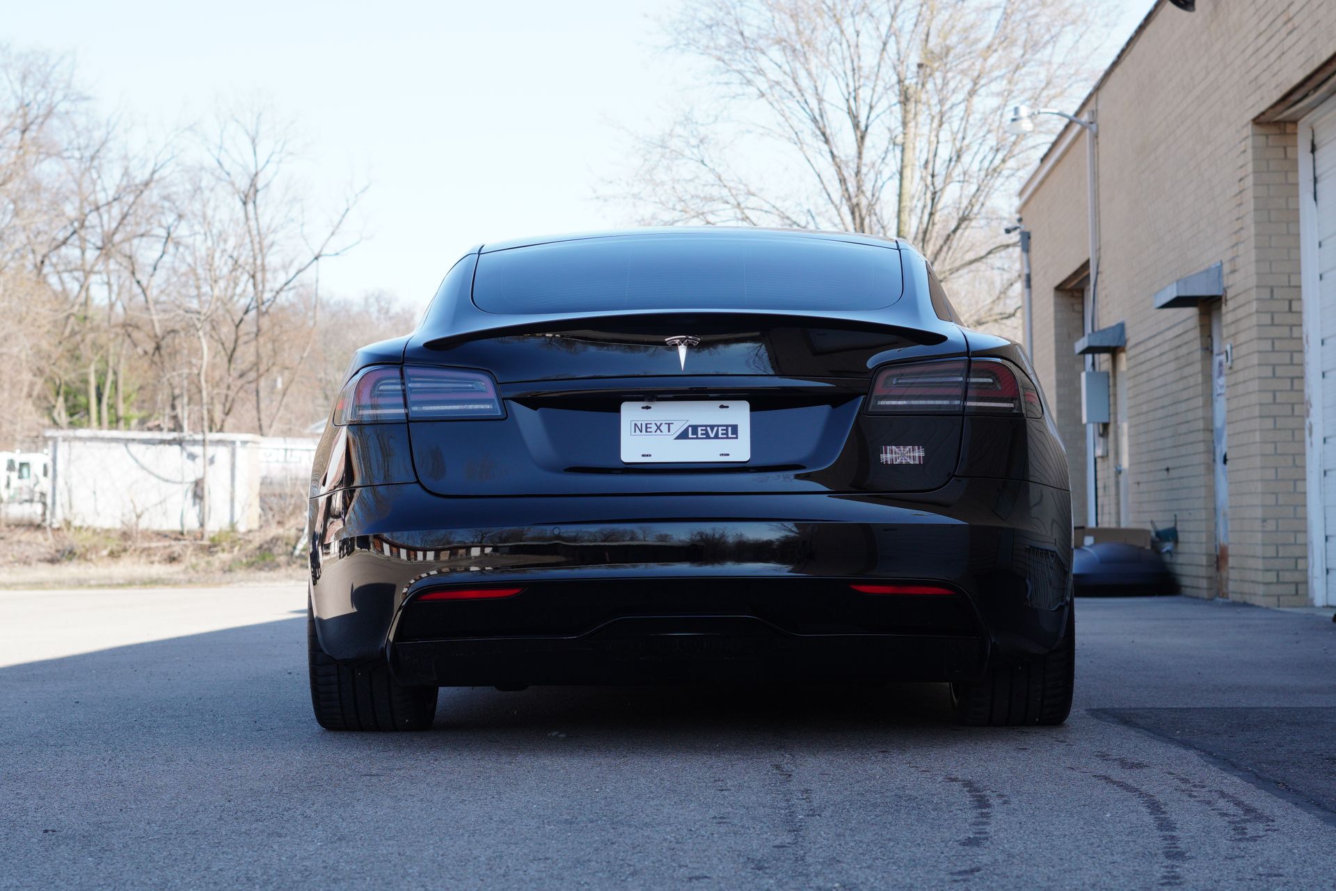 A black tesla model s is parked in front of a brick building.