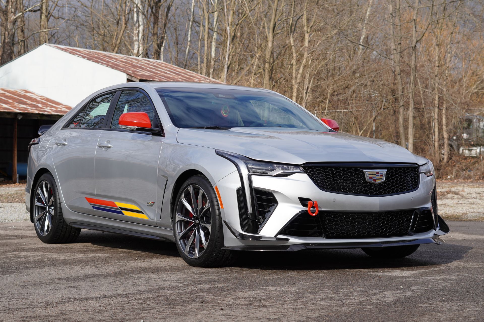 Silver Cadillac sports sedan with colorful side stripes and red mirror caps parked outdoors.