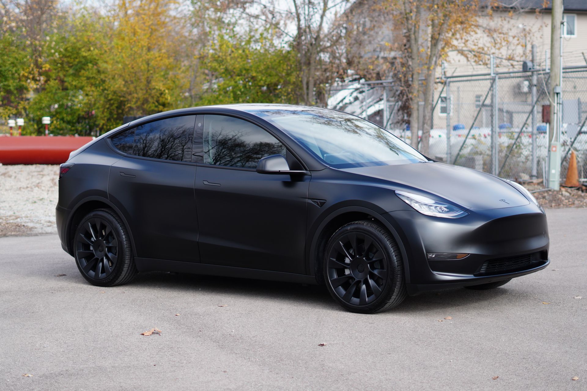 A black tesla model y is parked in a parking lot.