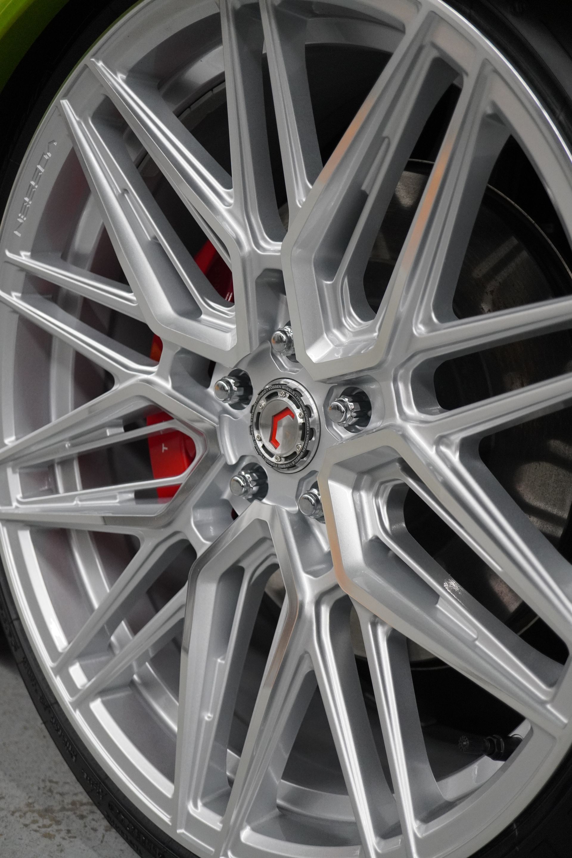 A close up of a silver wheel on a green car