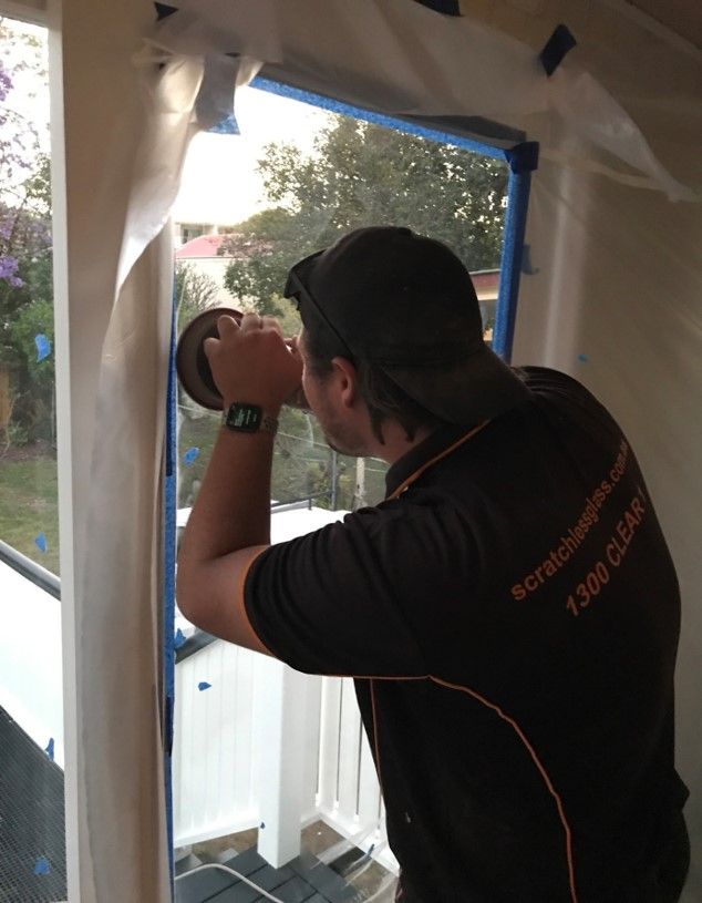 A Man Wearing Headphones Is Working On A Window — Scratchless Glass Australia in Maroochydore, QLD