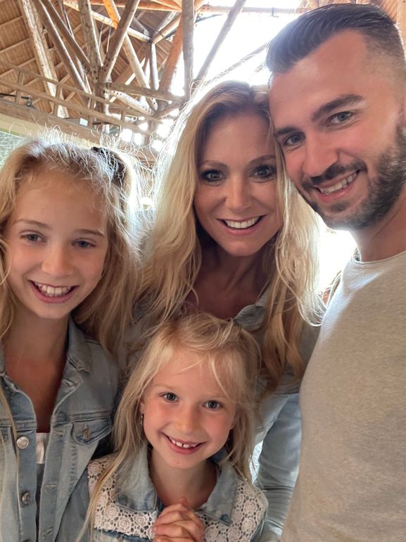 Familieselfie; een lachend stel met twee jonge meisjes, binnen, fel licht.