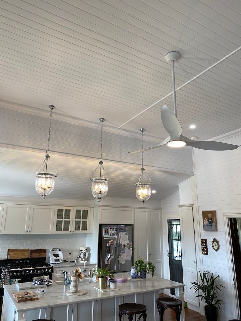 A White Kitchen with a Hanging Light and Fans — Brightway Electrical in Ballina, NSW