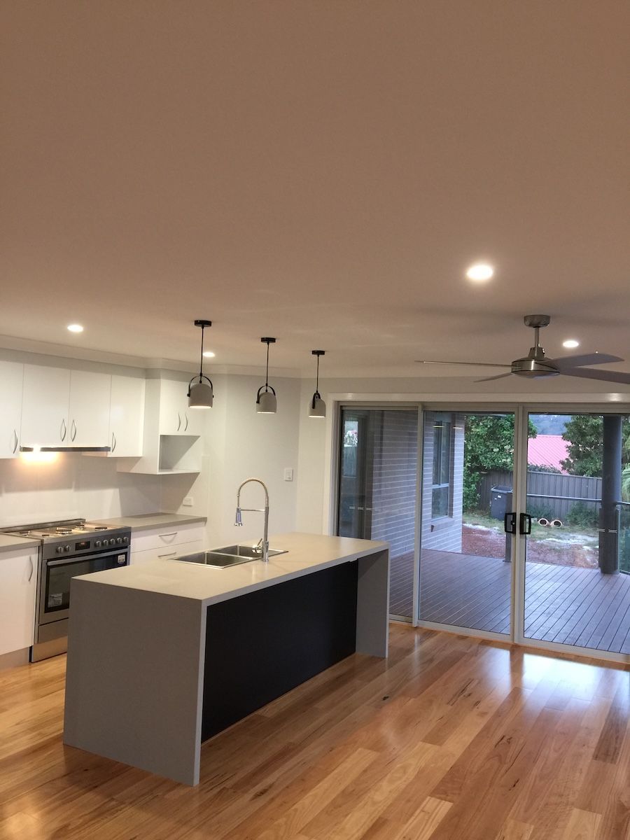 An Empty Kitchen with a Wooden Floor — Brightway Electrical in Ballina, NSW
