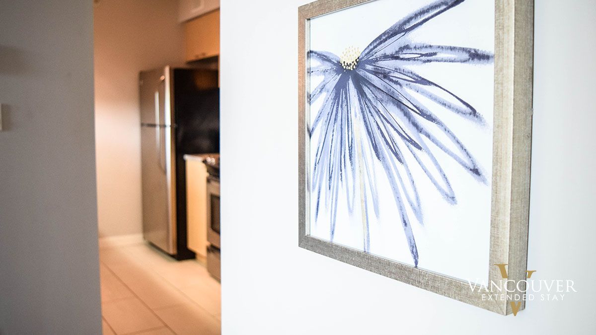 Painting of a blue tree hung on a hallway next to a kitchen