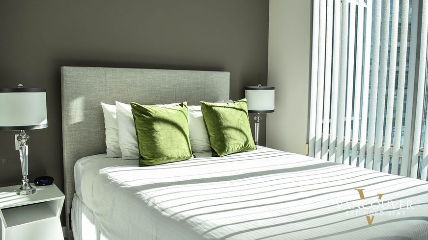 Four white pillows and 2 green pillows on top of a white queen size bed 