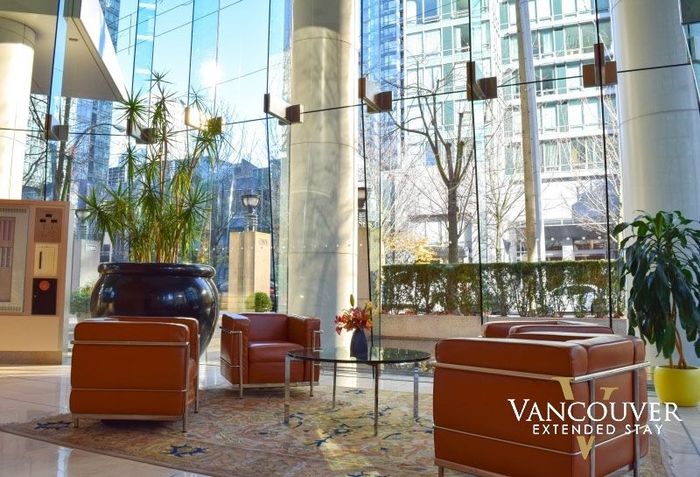 huge lounge with a glass table and three brown sofa chairs