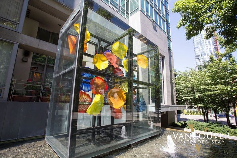 a sculpture of a flower encased in a glass case on a fountain outside of an apartment building