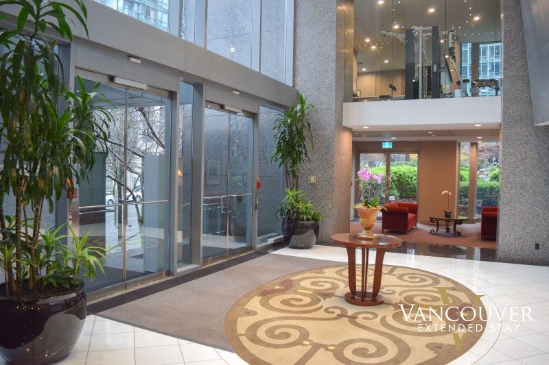 A lobby of a hotel with a wooden table in the middle next to a gym