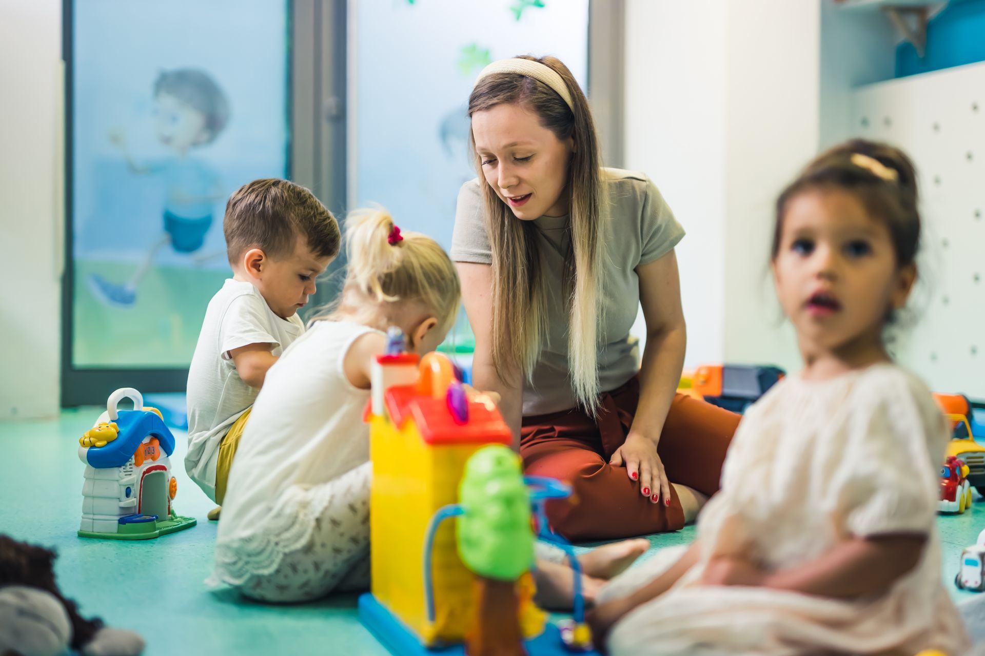 Kids and women playing with toys in a bright, welcoming day care center classroom.