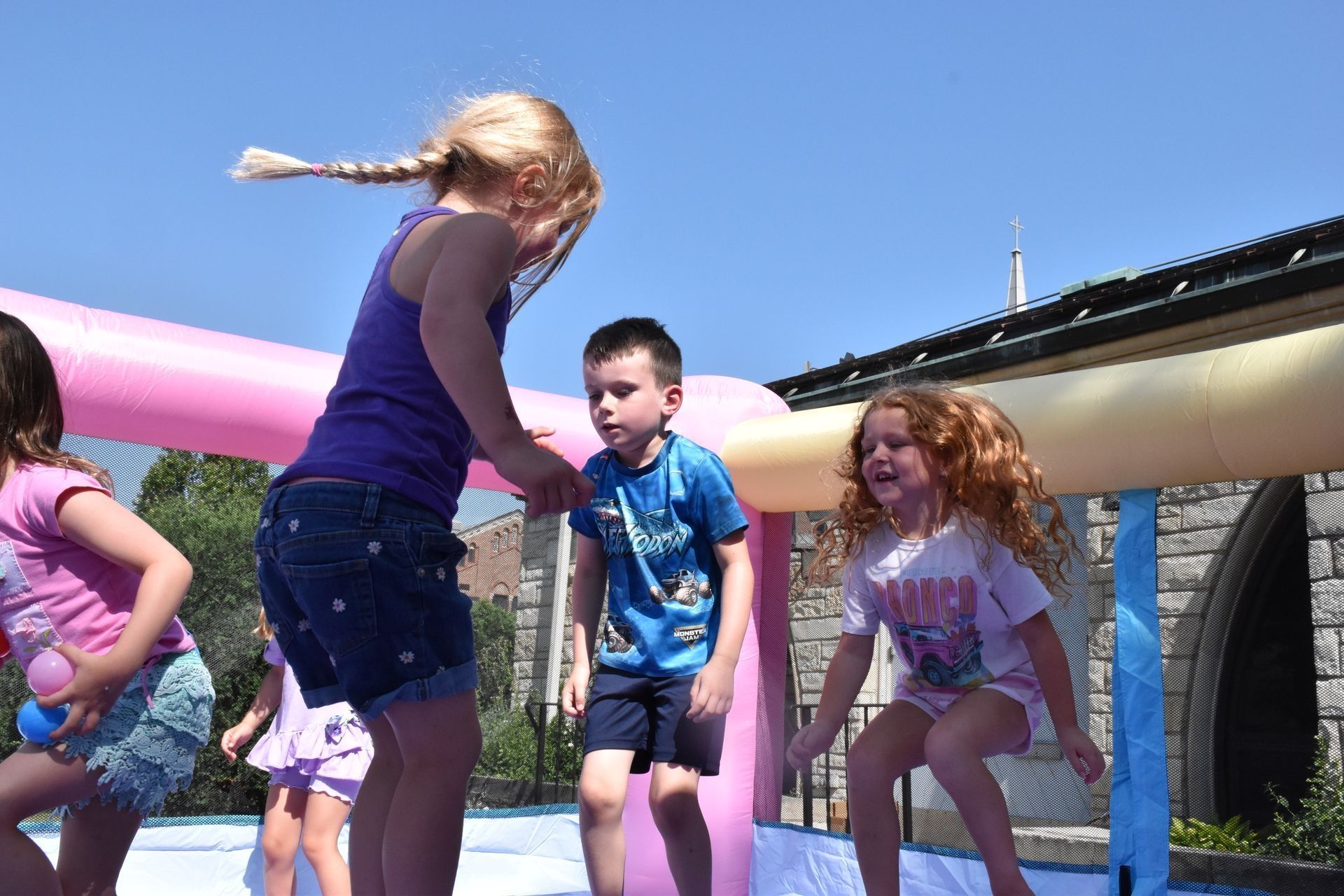 Children jumping in an inflatable water play structure on a sunny day.