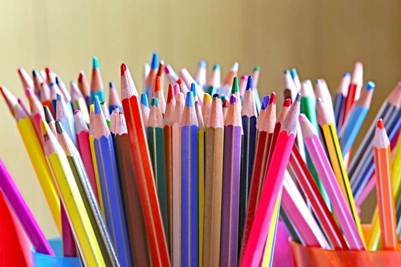 Young child coloring at a table with markers in a classroom setting.