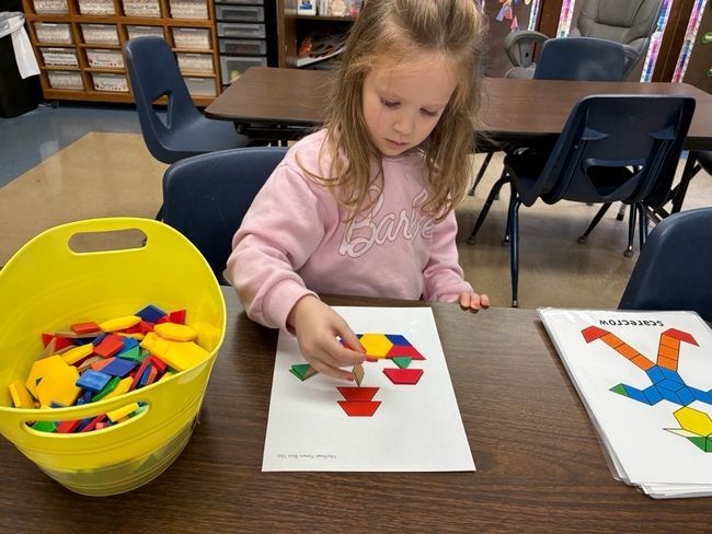 Children sit at a table coloring Earth drawings.