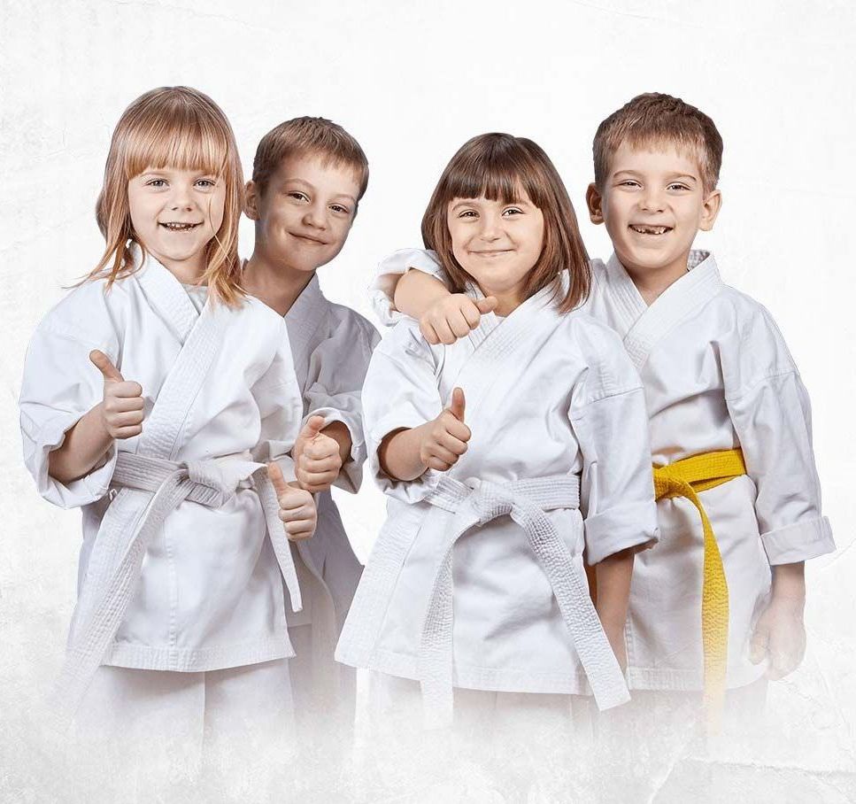 A group of children wearing white karate uniforms are giving a thumbs up