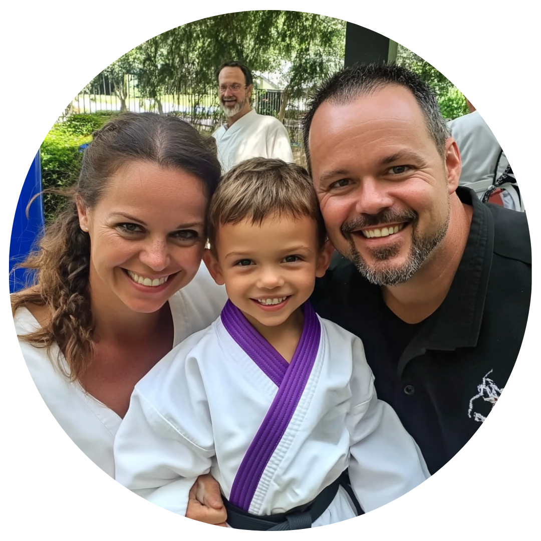 A man and woman are posing for a picture with a little boy in a karate uniform
