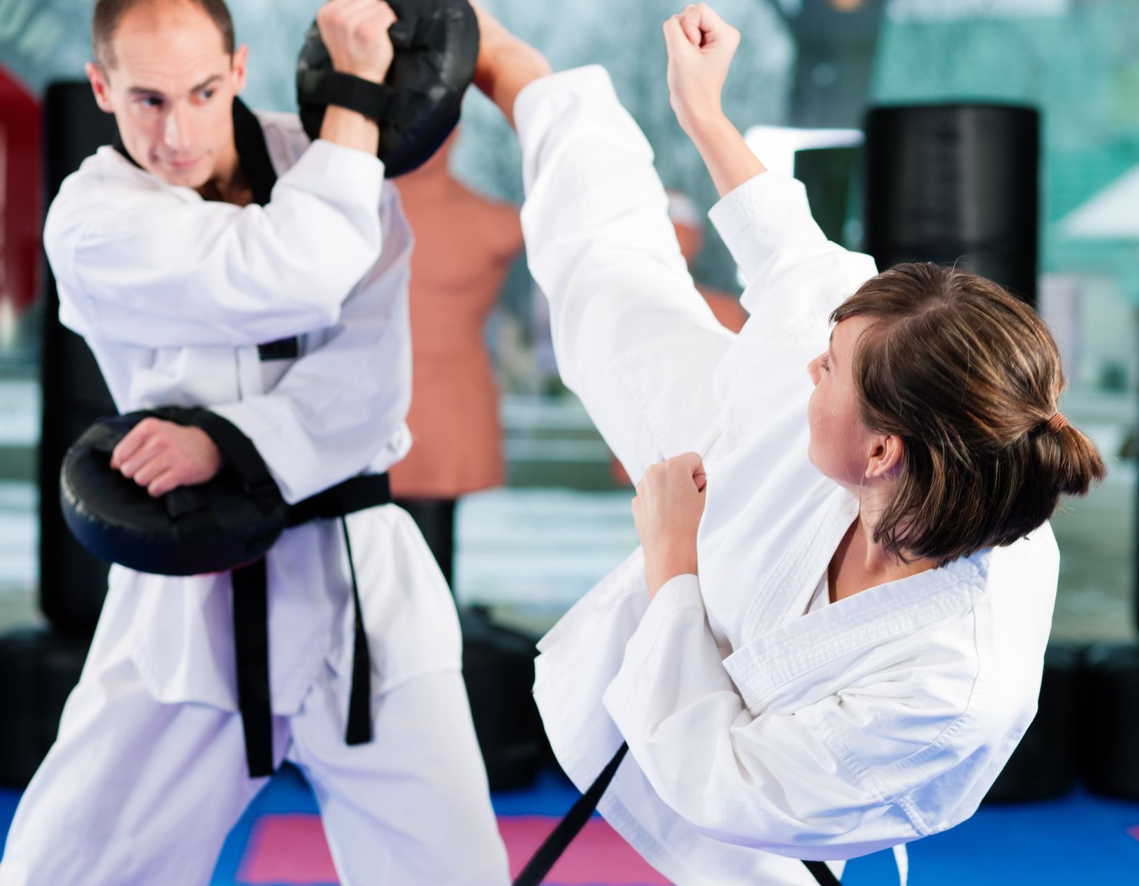 Two men are practicing judo on a mat in a gym.