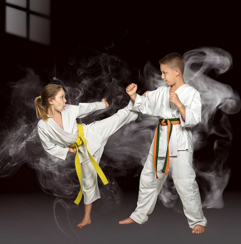 A boy and a girl are practicing karate in a dark room